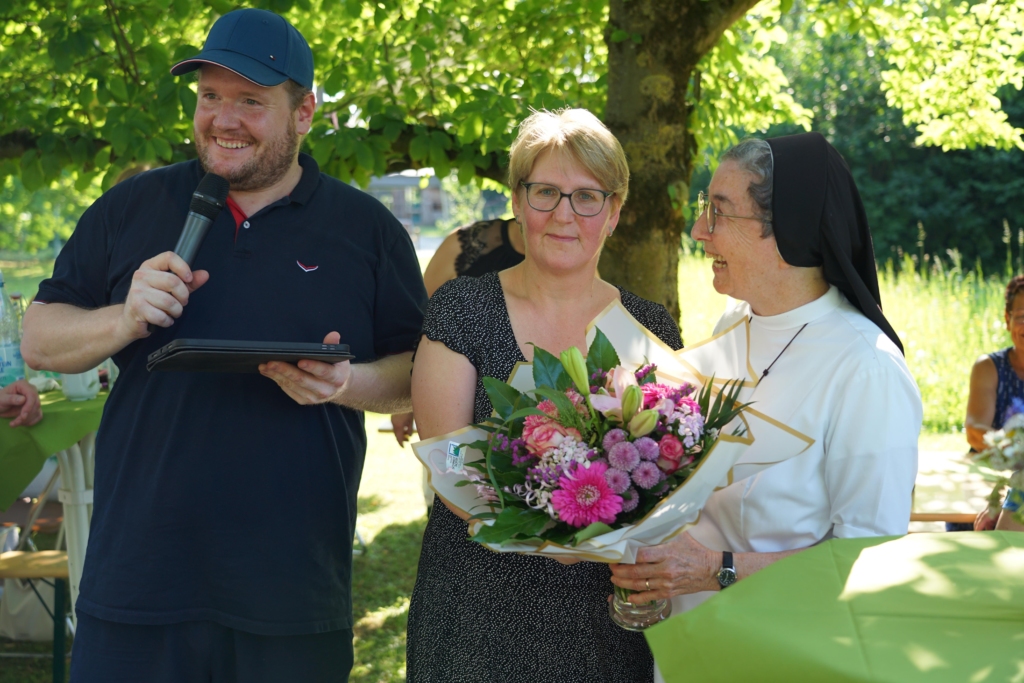 Dominik Korth und Petra Wiese von der Mitarbeitendenvertretung überreichten Schwester M. Angela einen Blumenstrauß. Foto: Michael Bodin / fcjm-presse