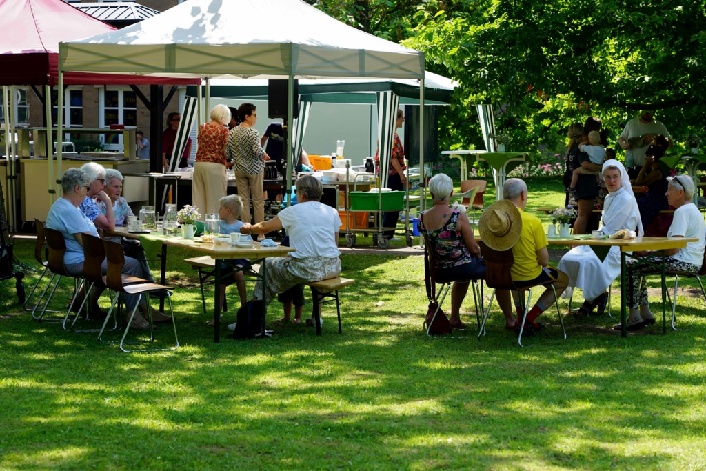 Im Schatten der großen Bäume nutzten die Besucherinnen und Besucher beim „Fest der Begegnung“ im Mutterhausgarten die Gelegenheit zum Austausch und zum gemütlichen Beisammensein. Foto: Michael Bodin / fcjm-presse